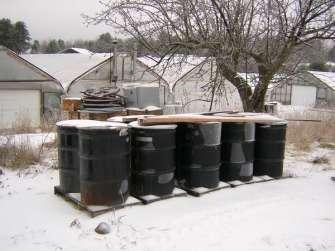 Storage Drums with covers and locking bands are set on pallets outside for