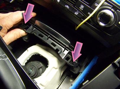The idea is to lift the rear of the shift boot and surrounding console cover. If you must pry at the perimeter, do so carefully, working in the area indicated by the lower arrows.