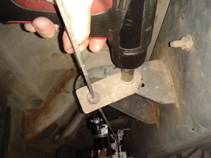 The emergency brake cable will be in the way so it must first be repositioned. Loosen the 13mm bolt that fastens the emergency brake cable support to the side of the frame rail.