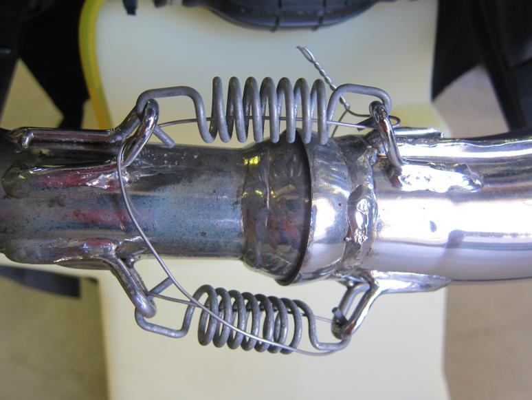 Thread the safety wire through the 3 muffler springs and through the 6 metal links on the muffler and the manifold. 4.