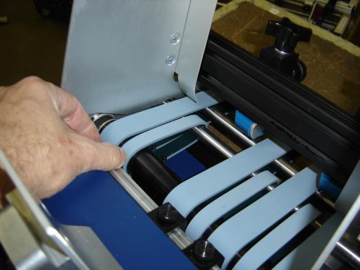To do this, loosen the paper guide locking lever, raise the paper guide up approximately ½ and slide OVER the belts.