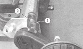 Remove square plugs from the swinging arm using a suitable tool Insert the damper mounting (1) into the slotted hole on the swinging arm Fit the damper mounting so that the arrow marking (2) faces in