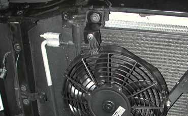 Using a 10mm socket, remove the bolt that secures the passenger side upper corner of the AC condenser.