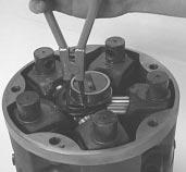 By hooking a finger under the piston lift up the piston, tapping the cylinder turn-on with a rubber hammer to loosen the piston from the shaft.