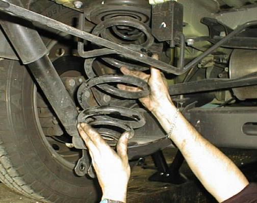 Loosen and remove the lower bolt on the shock absorbers.