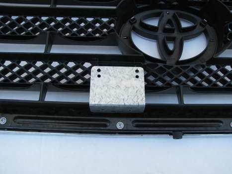 6. Set the bracket on the grille shell alligning the two top