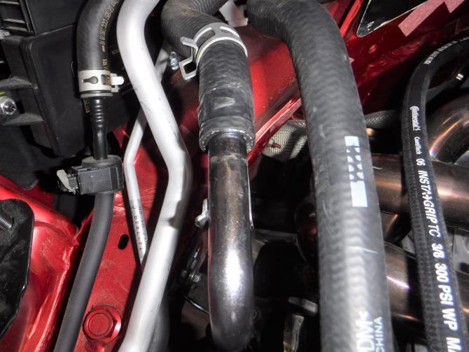 Place a cup or rag under the hose area. Wiggle the hose off the fitting. Only a small amount of coolant will come out.