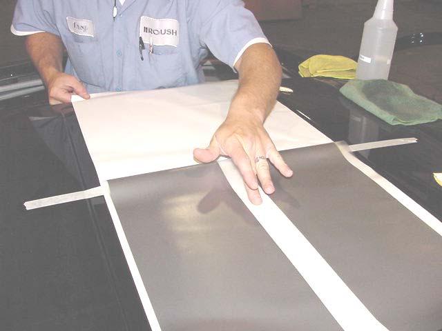15. Remove tape from the corners of one side, pull back decal to center 2 masking tape line.