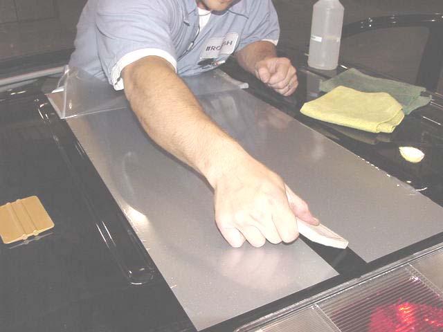 17. Working from the center outwards, use a sweeping motion with the felt squeegee to press out the air bubbles and adhere the decal to the flat surface as shown below. 18.