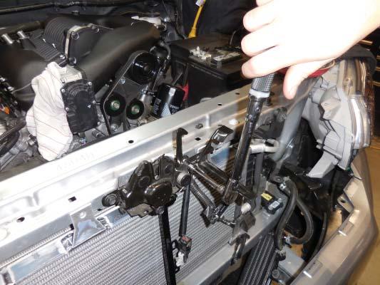 Reinstall the hood lock assembly. Torque the bolts to 12 Nm (9 ft lbf).