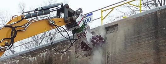 USA. AQ-4 on Case 330 excavator being used for demolition on dam spillway.
