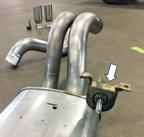 Raise the muffler assembly (as shown) and slide it into the