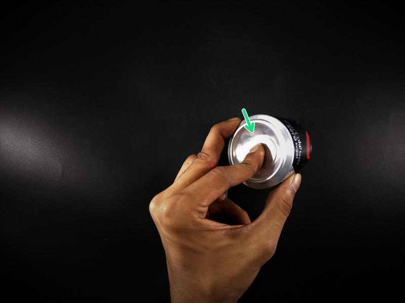 Hold the coin to the can with your finger and turn the can while