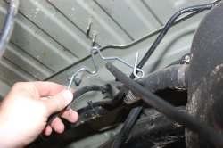45. Remove the e-brake cable bracket from the body using a 10mm wrench as shown in Photo 64. Remove the bracket from the e-brake cable as shown in Photo 65 to allow slack in the e-brake cables.