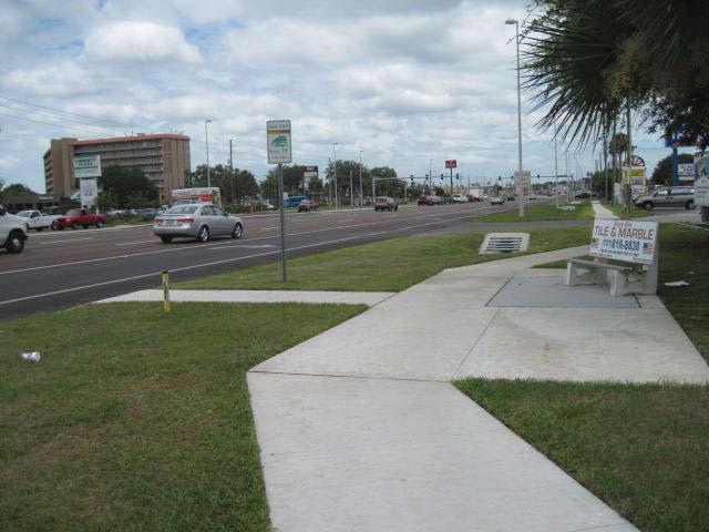 From across the street and behind the bus stop, take perpendicular shot of the entire bus stop and surrounding area.
