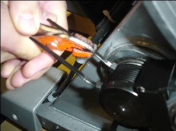 11. Grasp the pulley on the opposite side of the machine from the small pulley and rotate it back and