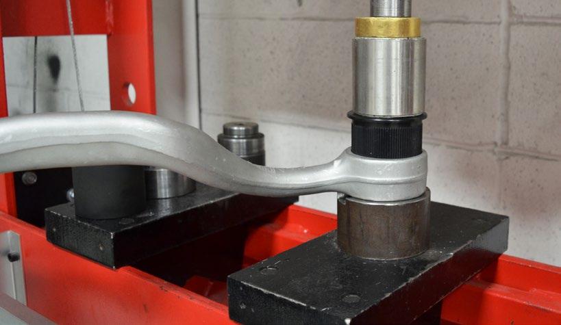 Use the press to completely remove the bushing and discard it. Align the bottom end of the bearing with the taper in the thrust arm bushing bore (inset photo).