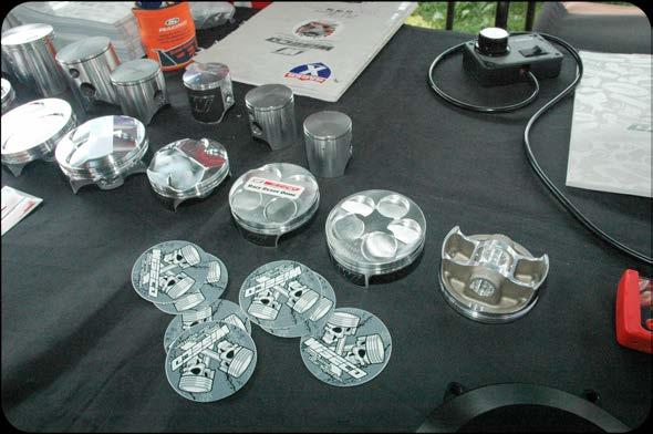 Four-stroke dirt bike pistons on display with deep cutaways that prevent piston-to-valve contact. Note the short piston skirts.