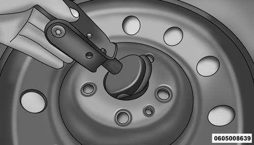 6. Pull the retainer through the center of the wheel. Preparations WHAT TO DO IN EMERGENCIES 295 1. Park the vehicle on a firm, level surface. Avoid ice or slippery areas. WARNING!