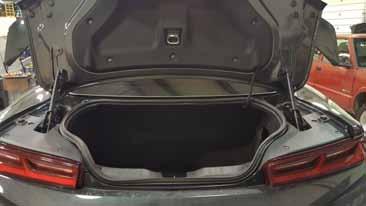 1. Open the trunk of the vehicle to access the battery. 2. Remove the battery access panel that is located in the trunk.