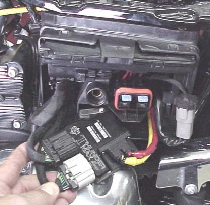 FXD-E: Starting at the rear cylinder head, route the oxygen sensor harness behind the coil and ECM caddy up through the frame opening as shown, then