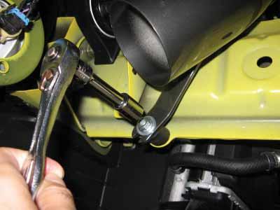 Under the vehicle, route the washer fluid hose and pump harness away from the
